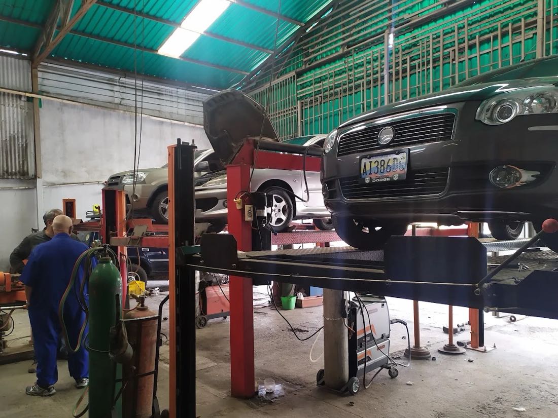 Mecánicos del taller Porturan trabajando, con un vehículo levantado en el puente y el equipo de soldadura al lado